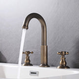 3-hole cross handle bathroom faucet with water flowing into a white sink