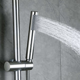 Brushed nickel handheld shower sprayer with water flow on gray tiled wall