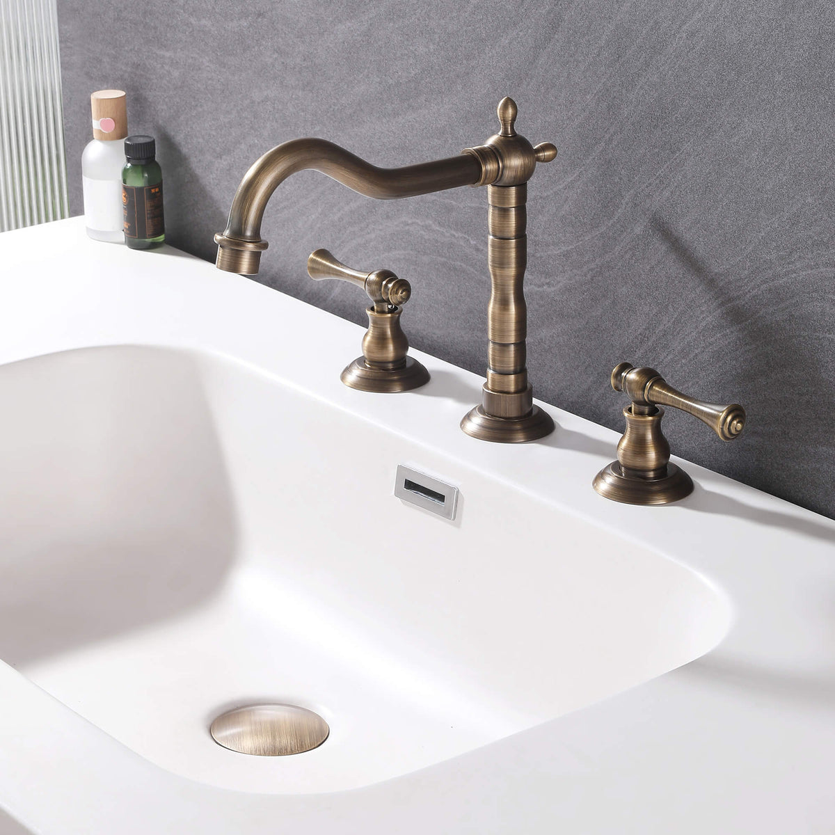 Antique brass widespread bathroom faucet installed on a white bathroom sink