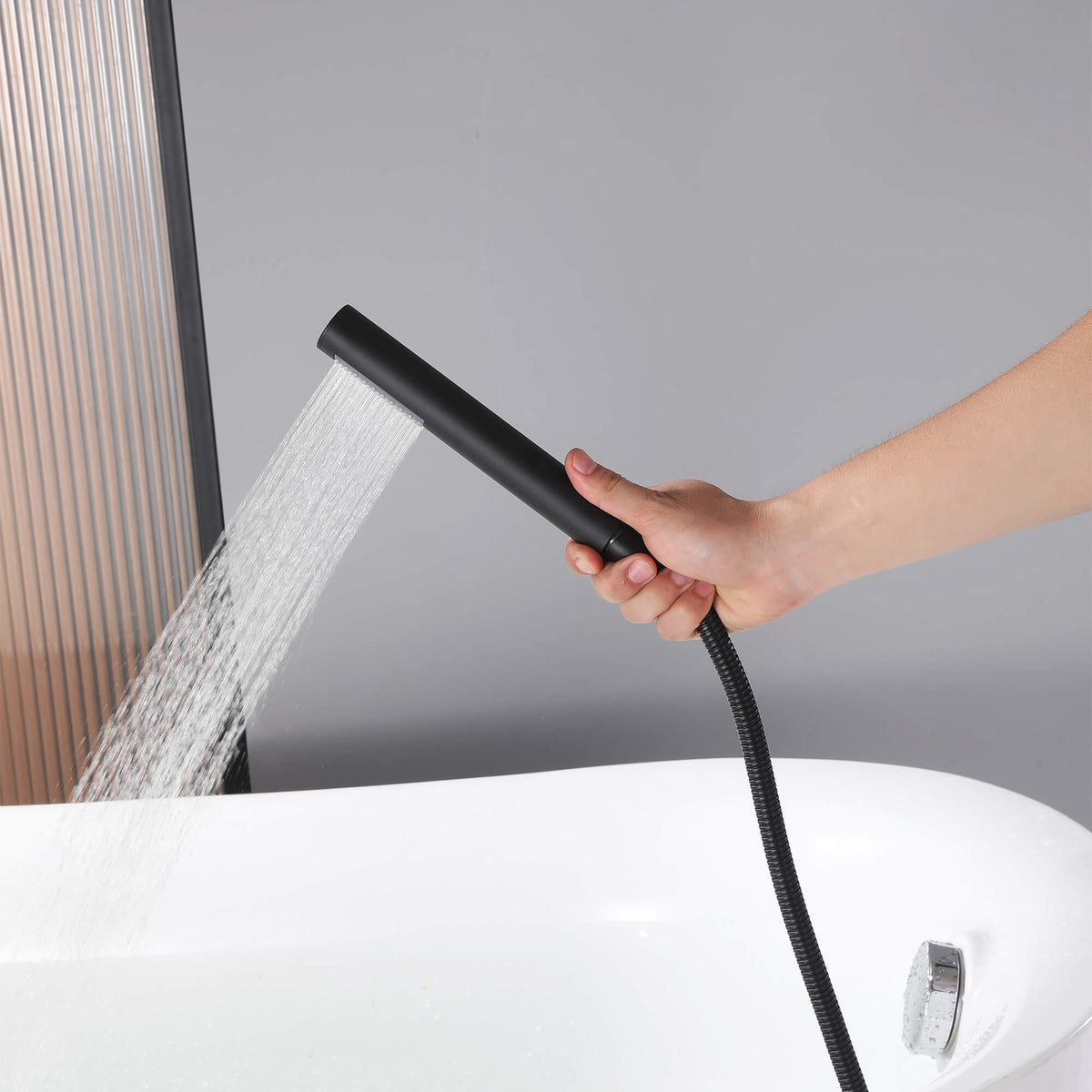 Matte black handheld shower for freestanding bathtub faucet with flowing water