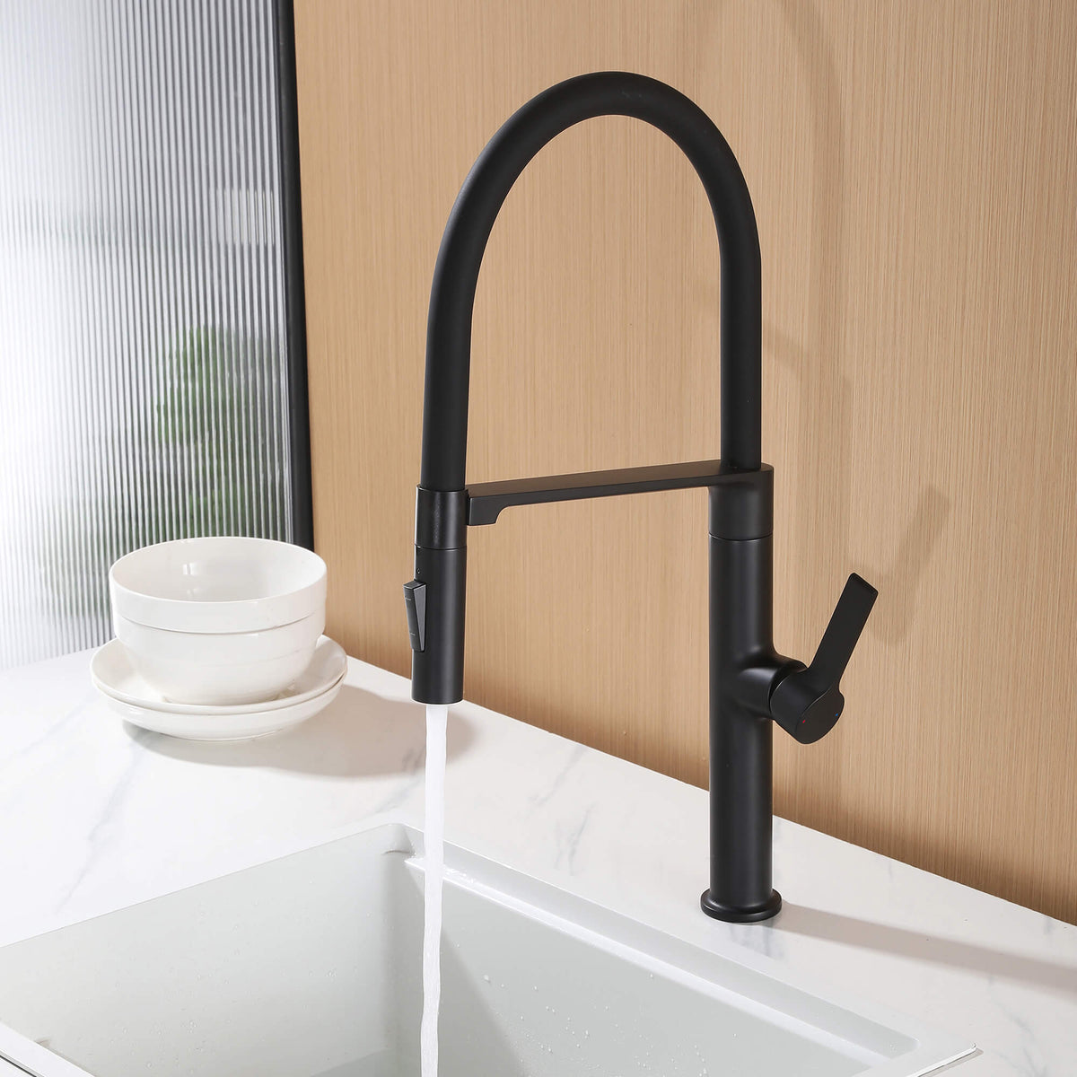 Black commercial style kitchen faucet installed on sink with steady stream water flow