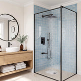 Matte black overhead shower delivering full-body rainfall inside a glass enclosure with matching handheld sprayer and bath spout