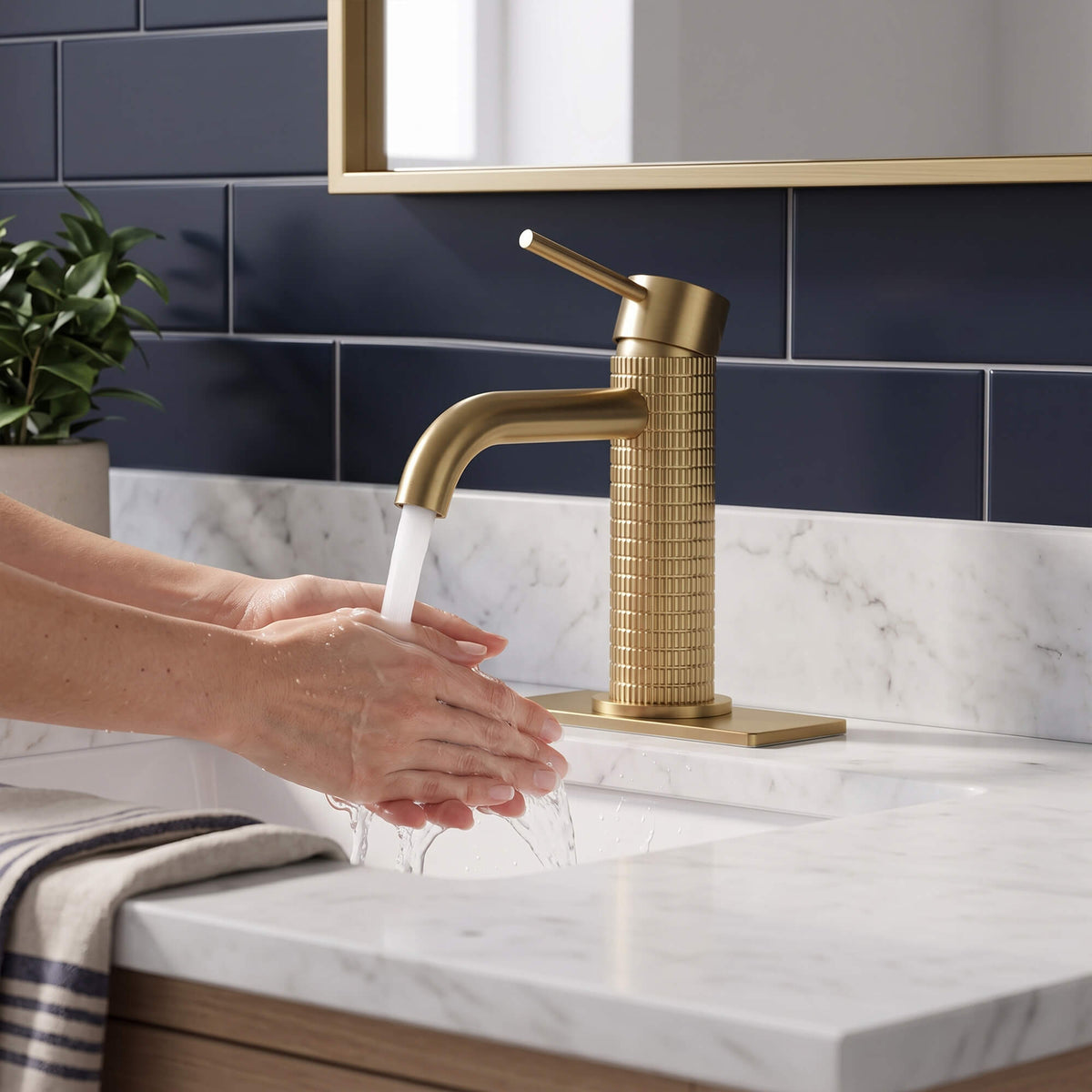 Brushed gold bathroom faucet with hands washing under flowing water