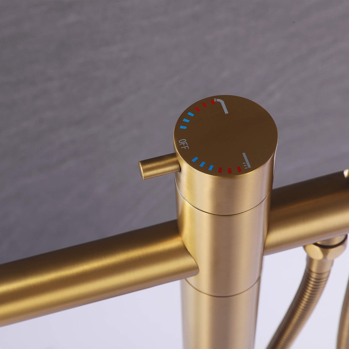 Brushed gold bathtub faucet control with hot, cold, and function markings