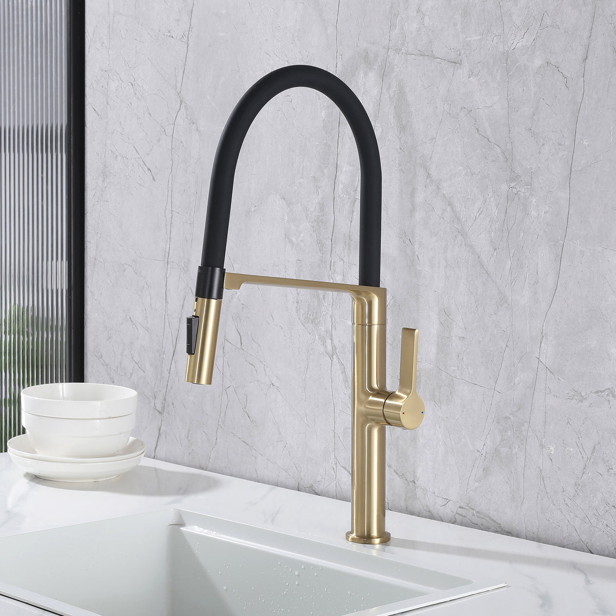Brushed gold and black pull-down kitchen faucet installed on a modern kitchen sink