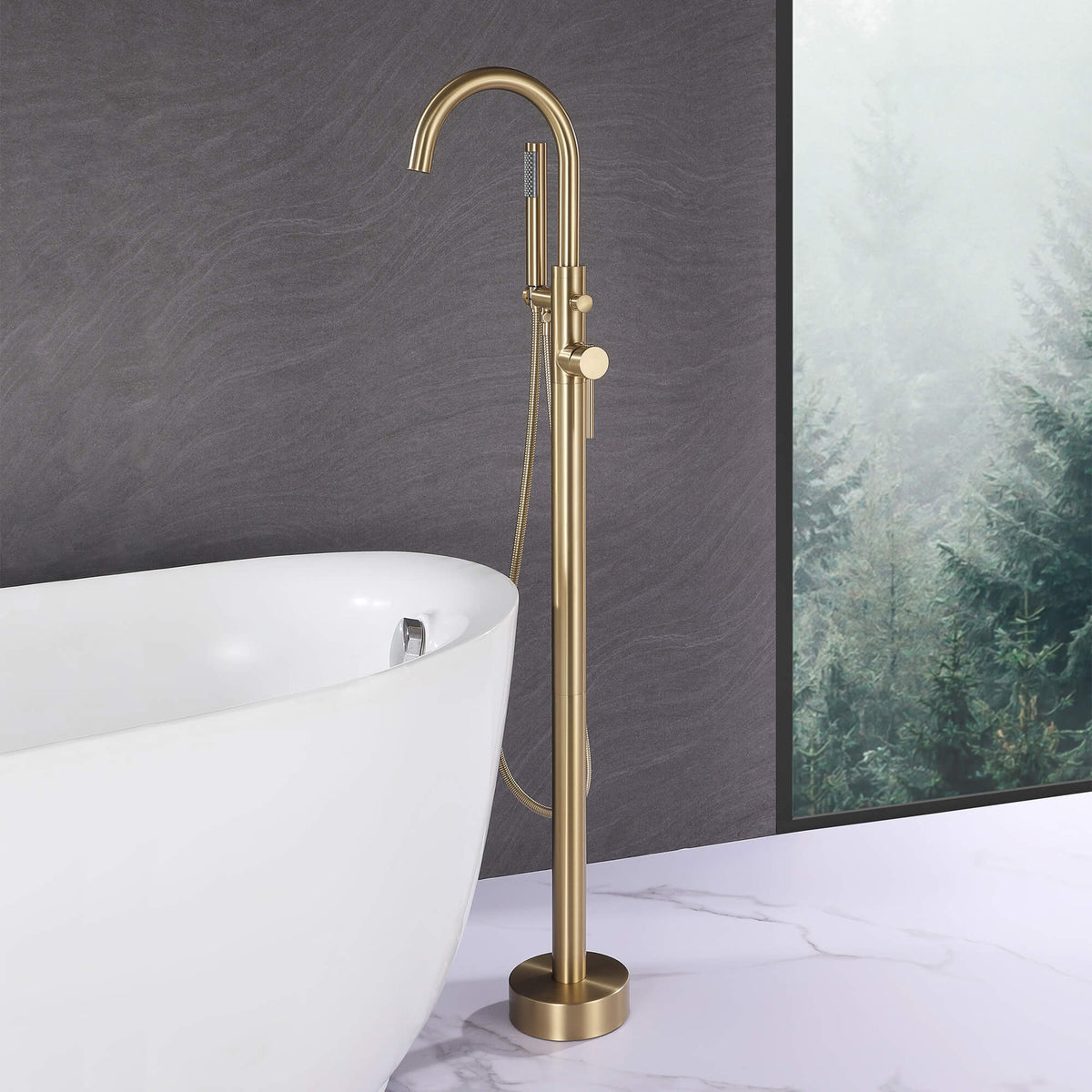 Brushed gold freestanding bathtub faucet with hand shower beside a white soaking tub