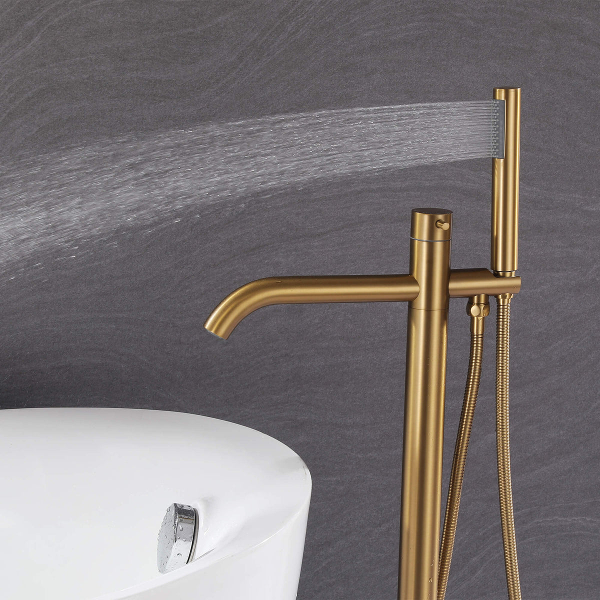 Handheld shower on brushed gold freestanding tub filler delivering a wide rinsing spray