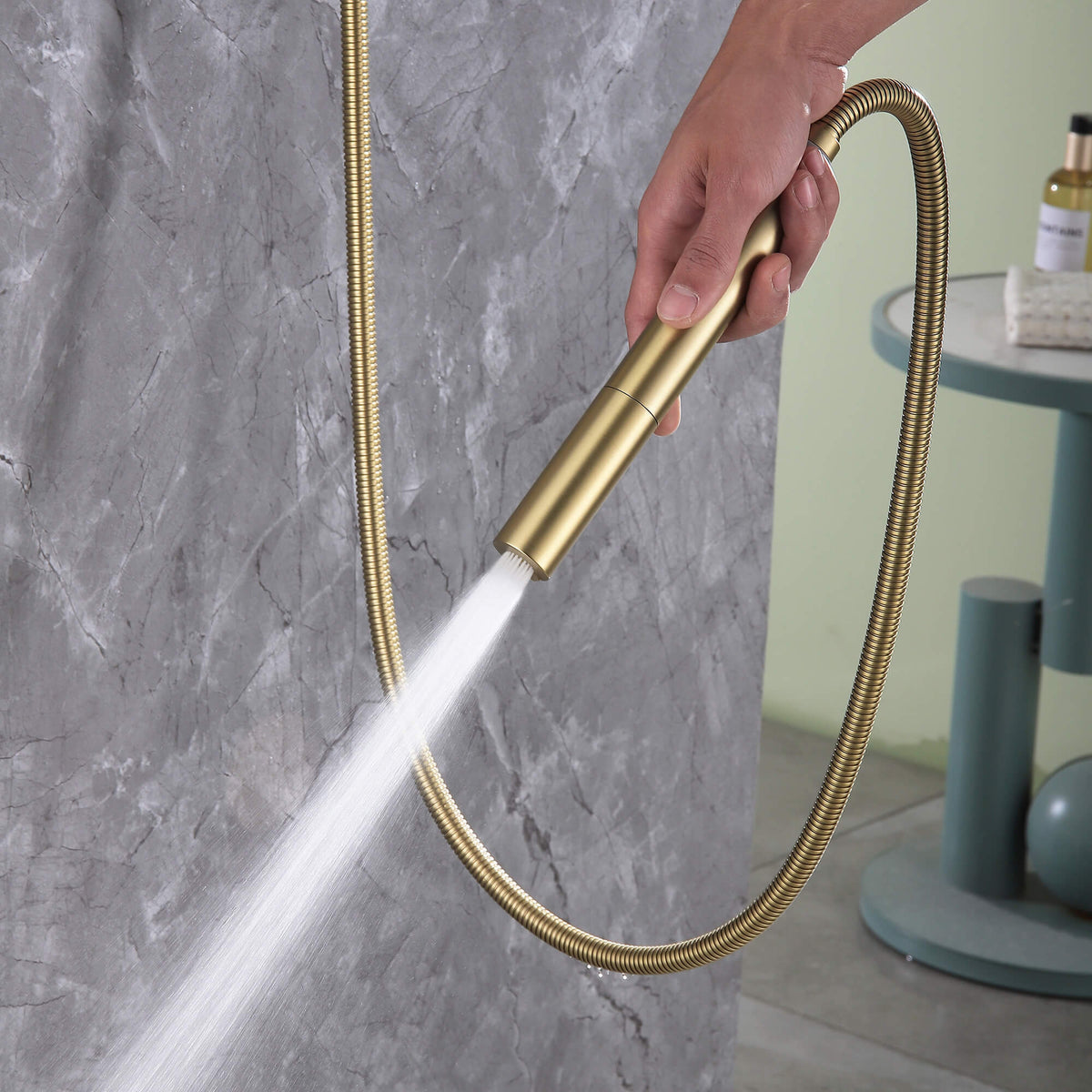 Brushed gold handheld shower wand used as a spray gun, showing powerful water flow for cleaning or rinsing.