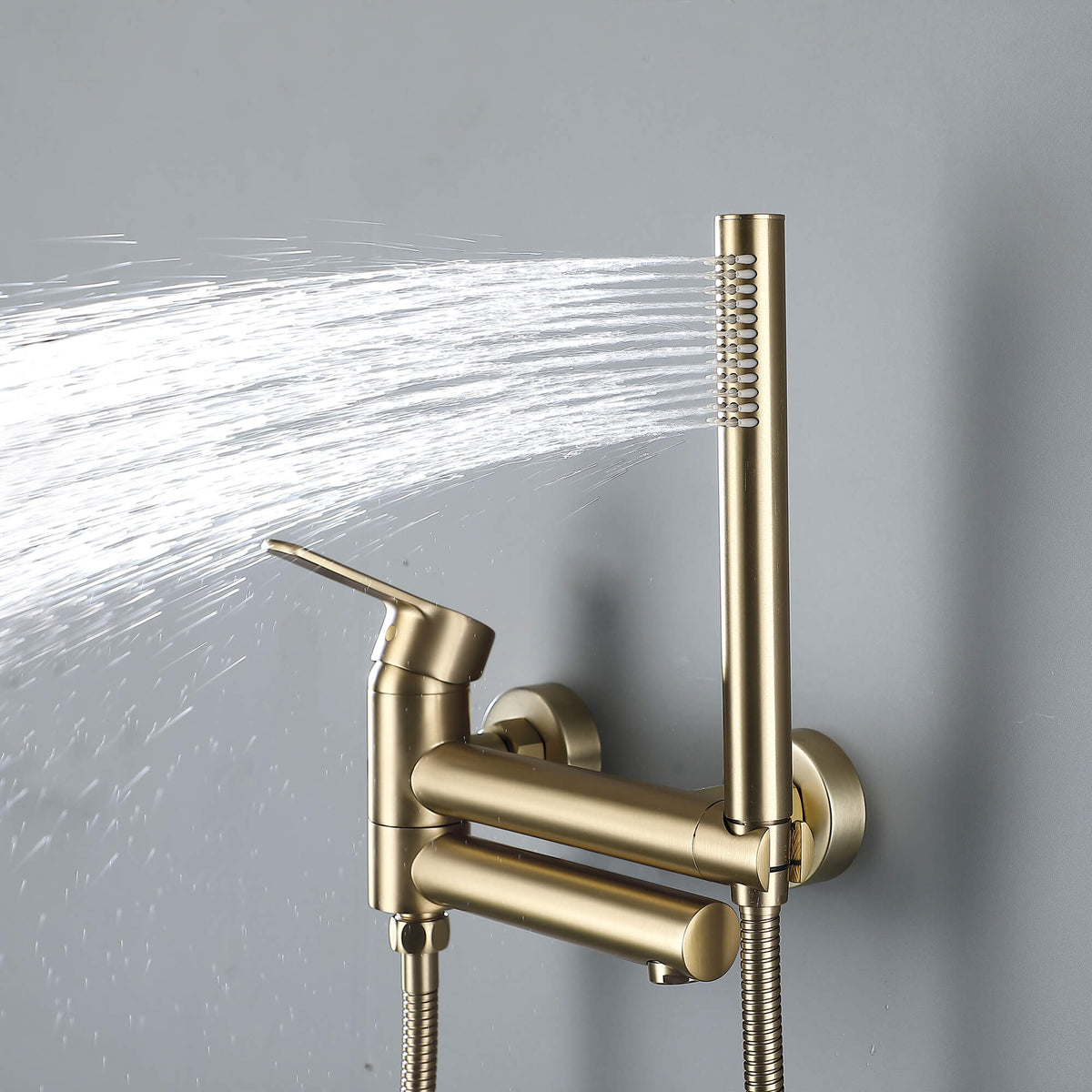 Brushed gold handheld shower spraying water beside the wall-mounted tub faucet