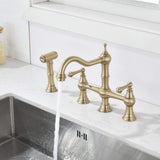 Brushed gold kitchen bridge faucet with high arc spout running over the sink