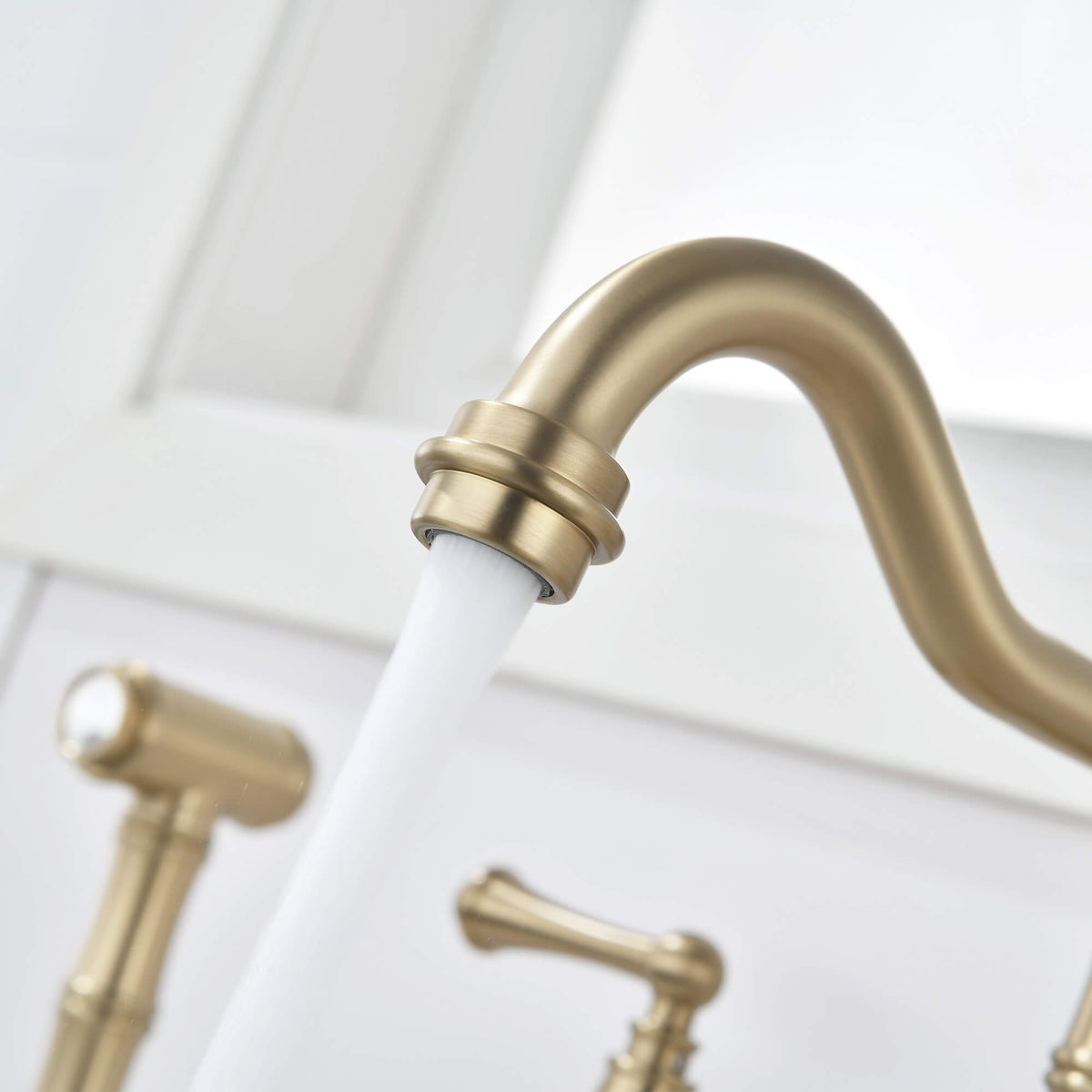 Close-up of brushed gold kitchen faucet spout and aerator with running water