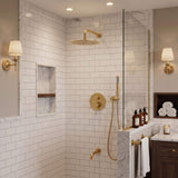 Brushed gold rain shower system with rainfall shower head, handheld shower and tub spout in a marble tile bathroom