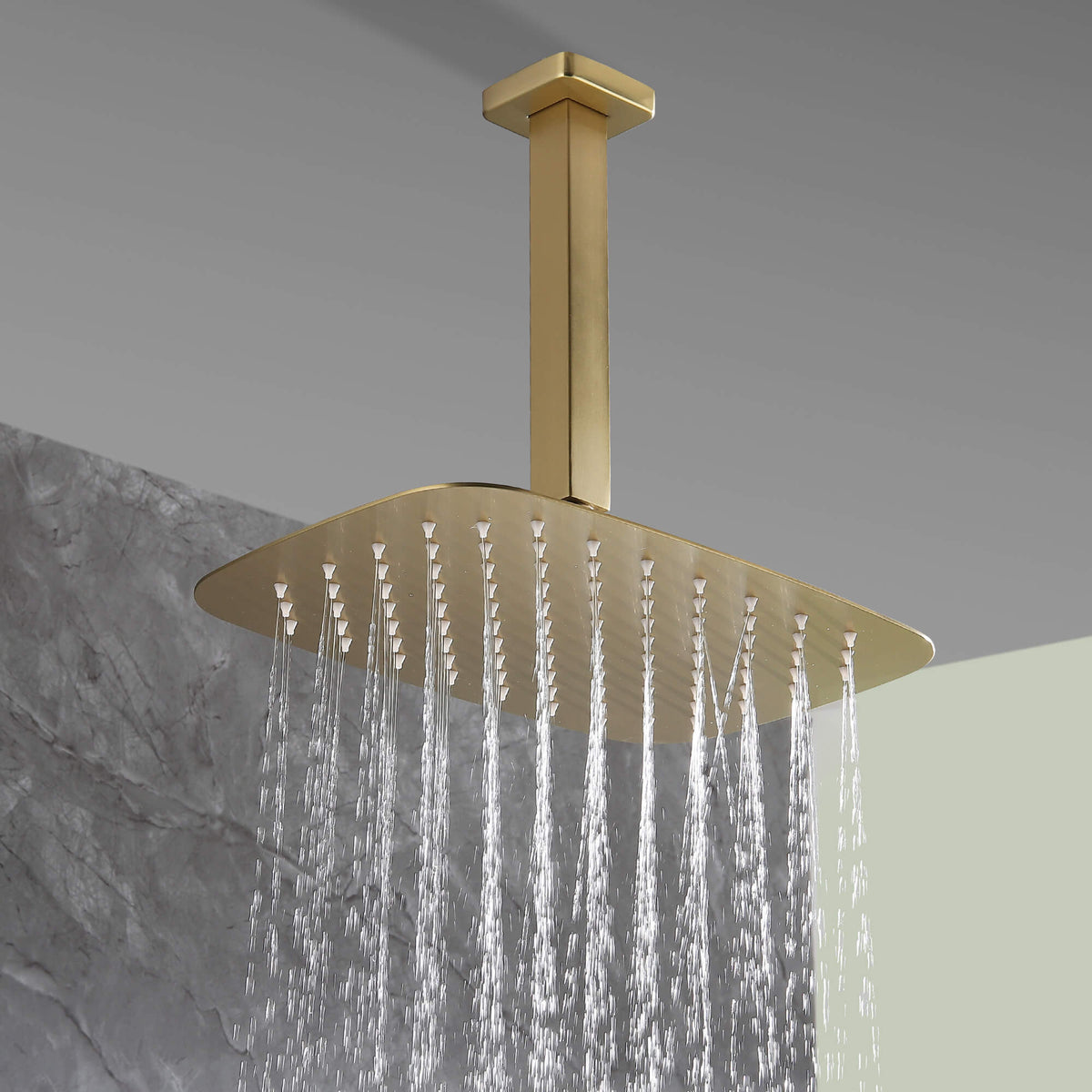 Close-up of brushed gold rainfall shower head spraying water, modern bathroom fixture.