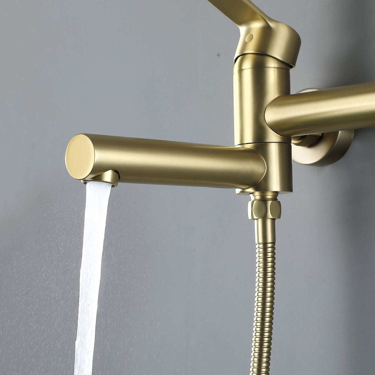 Close-up of brushed gold wall-mounted tub faucet spout with steady water flow