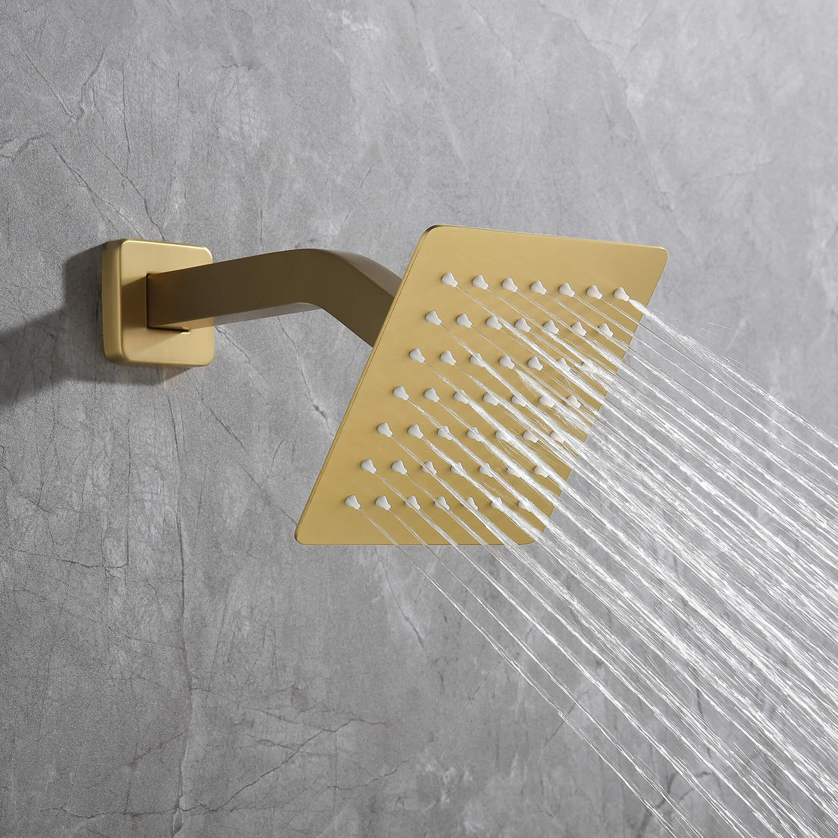 Close-up of brushed gold wall-mounted square shower head with strong spray stream.