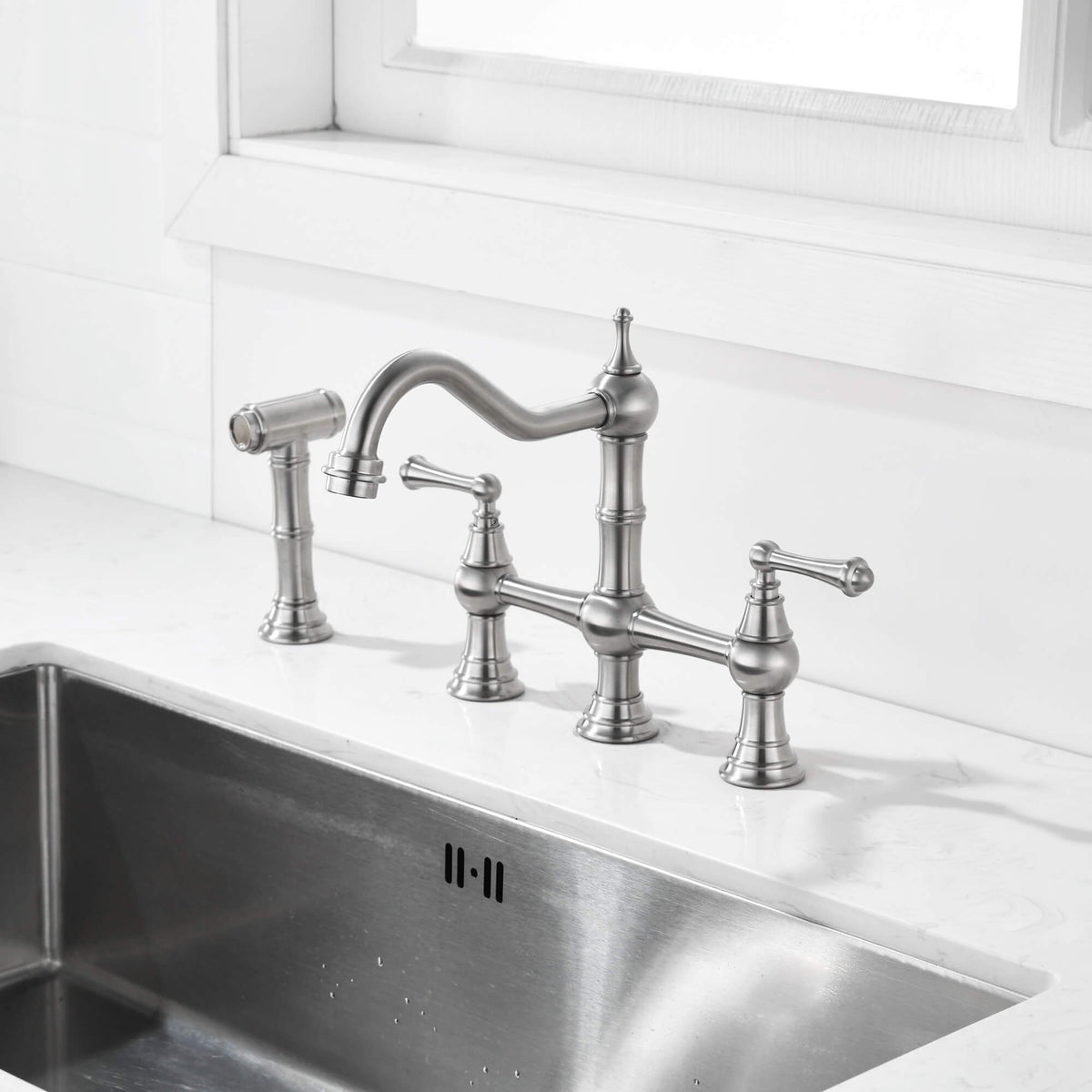 Brushed nickel bridge kitchen faucet with side spray installed on a kitchen sink