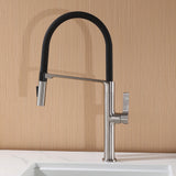 Brushed nickel commercial style kitchen faucet installed on white sink with wood backsplash