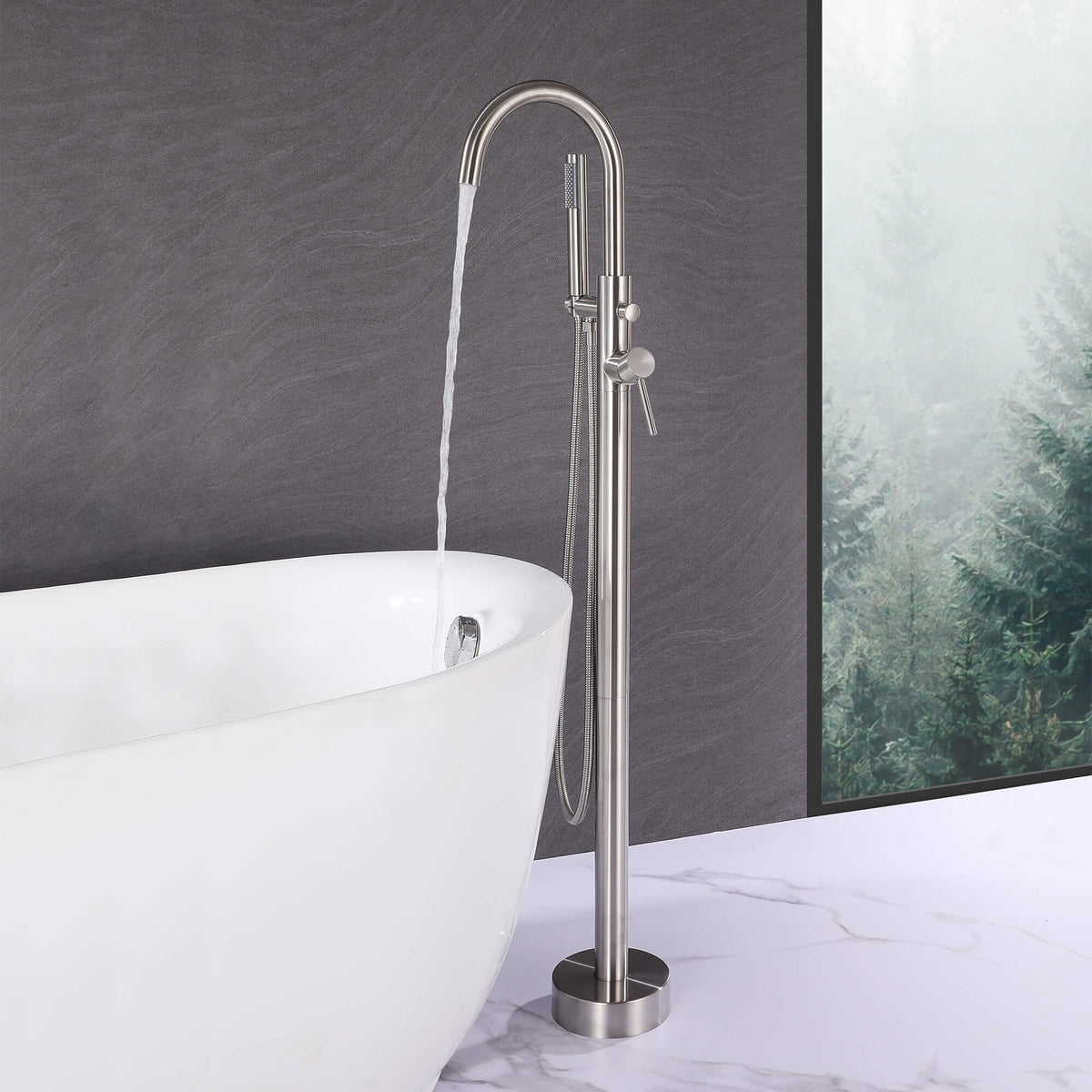 Brushed nickel floor mount tub filler running water into a freestanding bathtub