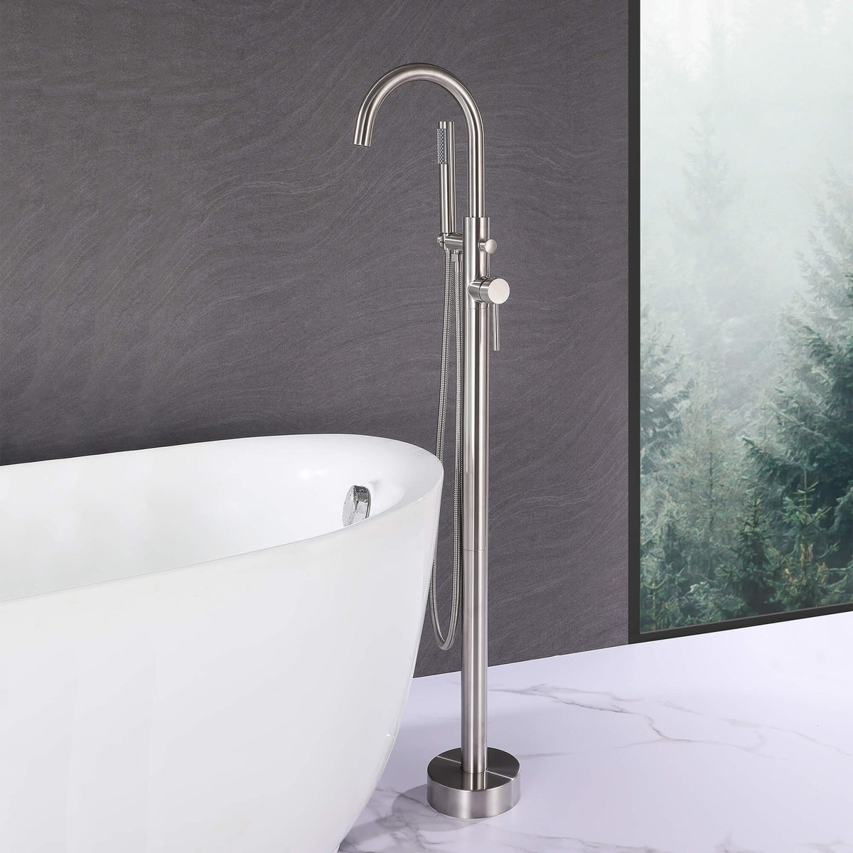Brushed nickel freestanding bathtub faucet with hand shower beside a white soaking tub
