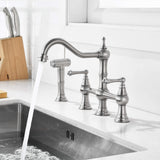 Brushed nickel kitchen bridge faucet with high arc swivel spout running over kitchen sink