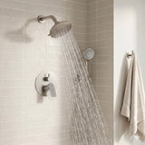 Round multi-function shower head delivering a wide rainfall stream in a modern neutral-tile bathroom