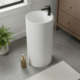 Modern white round pedestal sink installed in a bathroom with classic decor, wall sconces and wood cabinets.