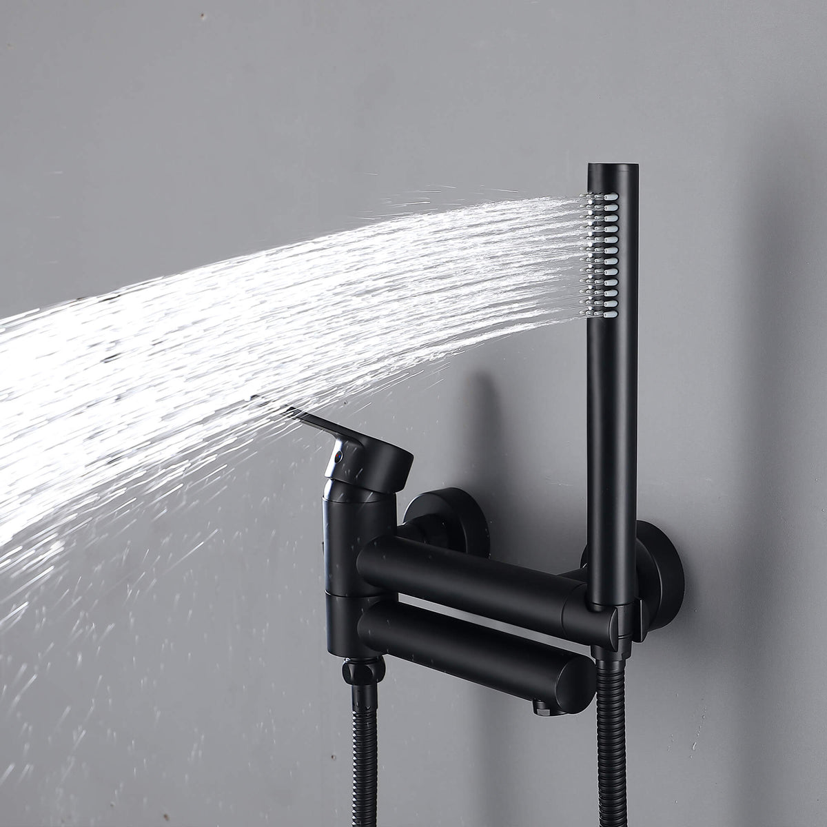 Matte black handheld shower spraying water beside the wall-mounted tub faucet
