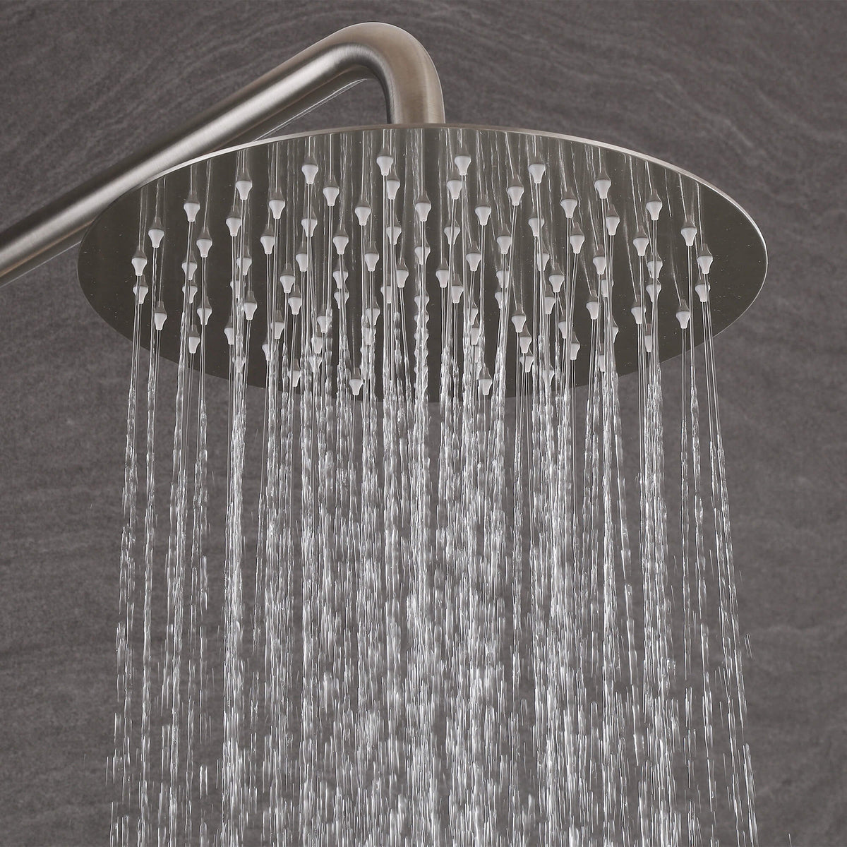 Water flowing from the round brushed nickel rain shower head of the JK0564 outdoor shower system.