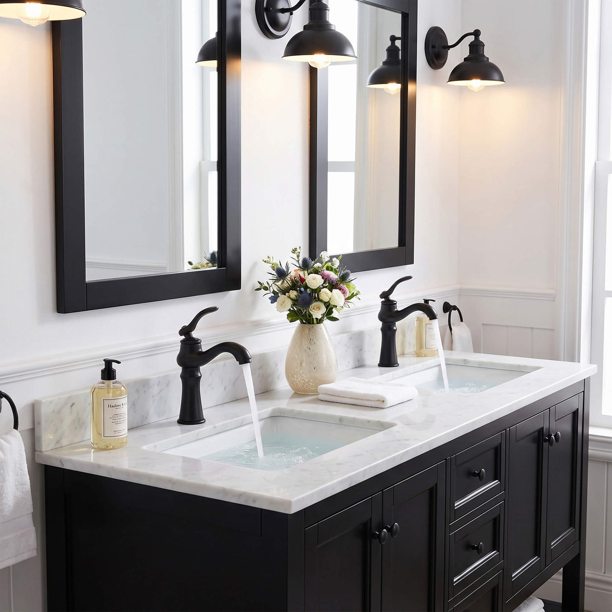 Pair of matte black bathroom faucets with running water in a double vanity setup