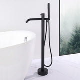 Matte black floor mount tub filler with handheld shower beside a freestanding bathtub