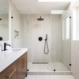 Matte black shower system with rain shower head, handheld shower and wall-mounted control valve in a modern bathroom