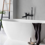 Matte black wall-mount tub filler with hand shower above a freestanding bathtub