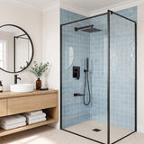 Modern blue-tile bathroom featuring a black square rain shower, slim hand wand, concealed controls and wall-mounted tub filler