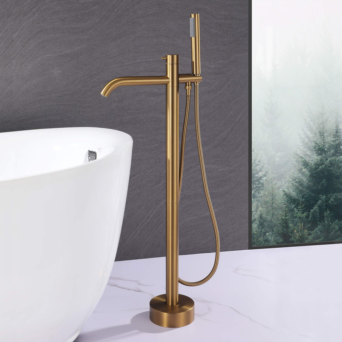 Modern brushed gold floor mount tub filler with handheld shower beside a freestanding bathtub