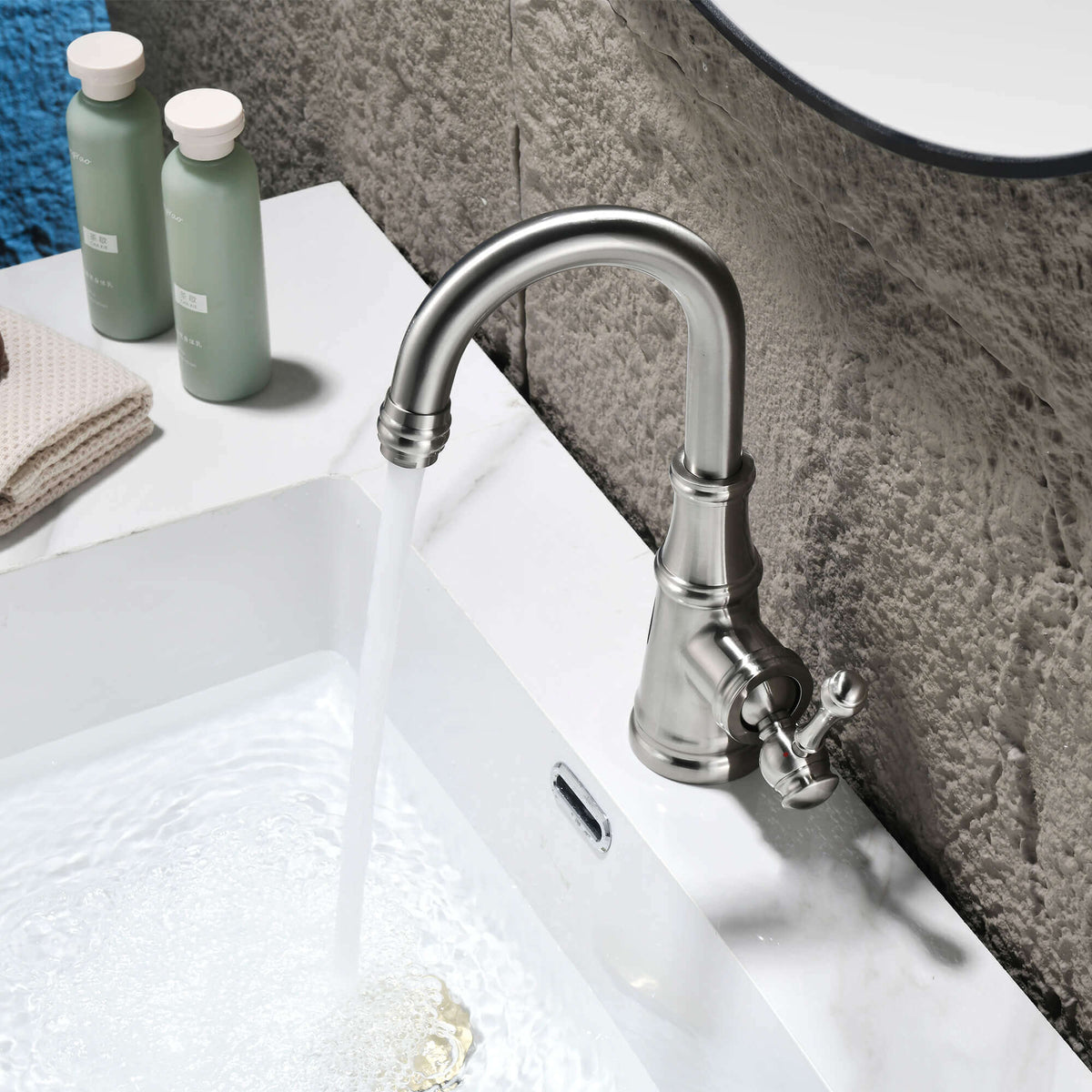 Modern brushed nickel basin faucet installed on white ceramic bathroom sink