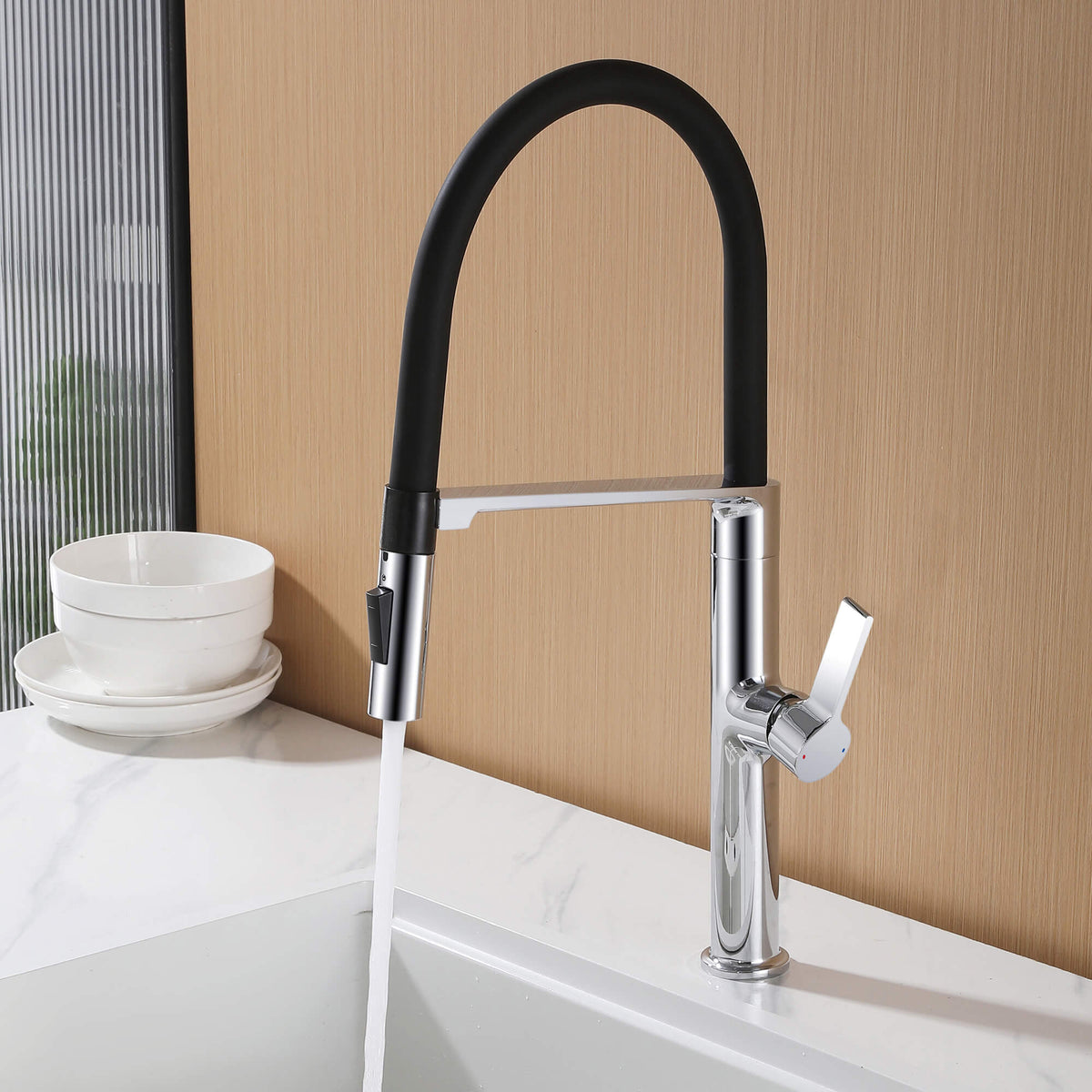 Polished chrome kitchen faucet with black flexible hose running stream water into sink