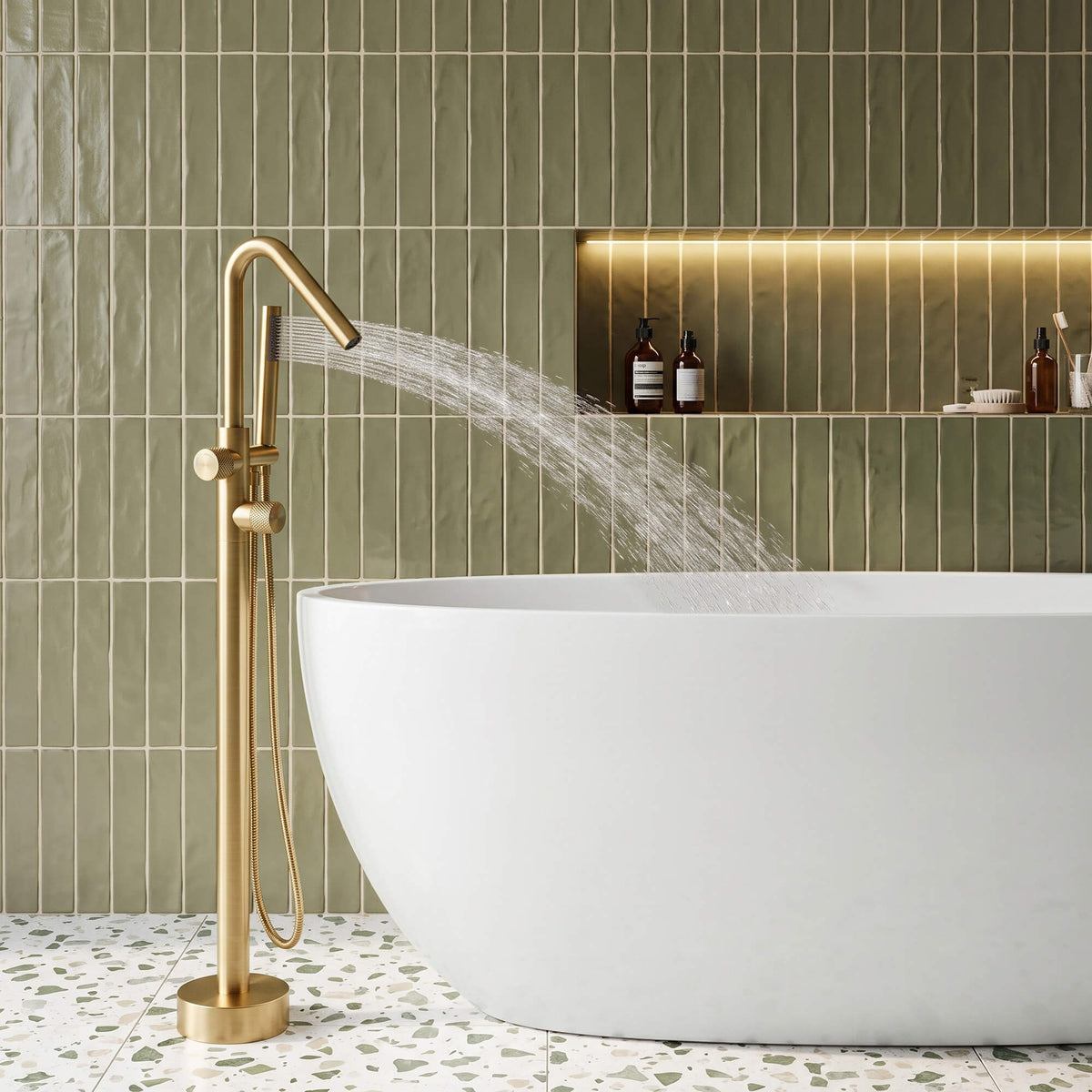 RB1352 brushed gold freestanding tub filler with handheld shower spraying water into a white freestanding bathtub.