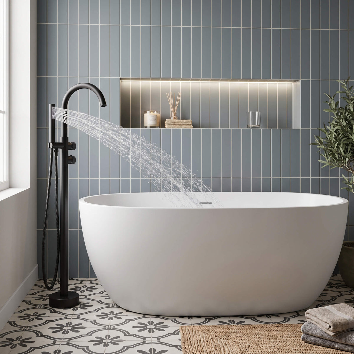 Matte black floor mounted tub filler with handheld shower spraying into a freestanding bathtub