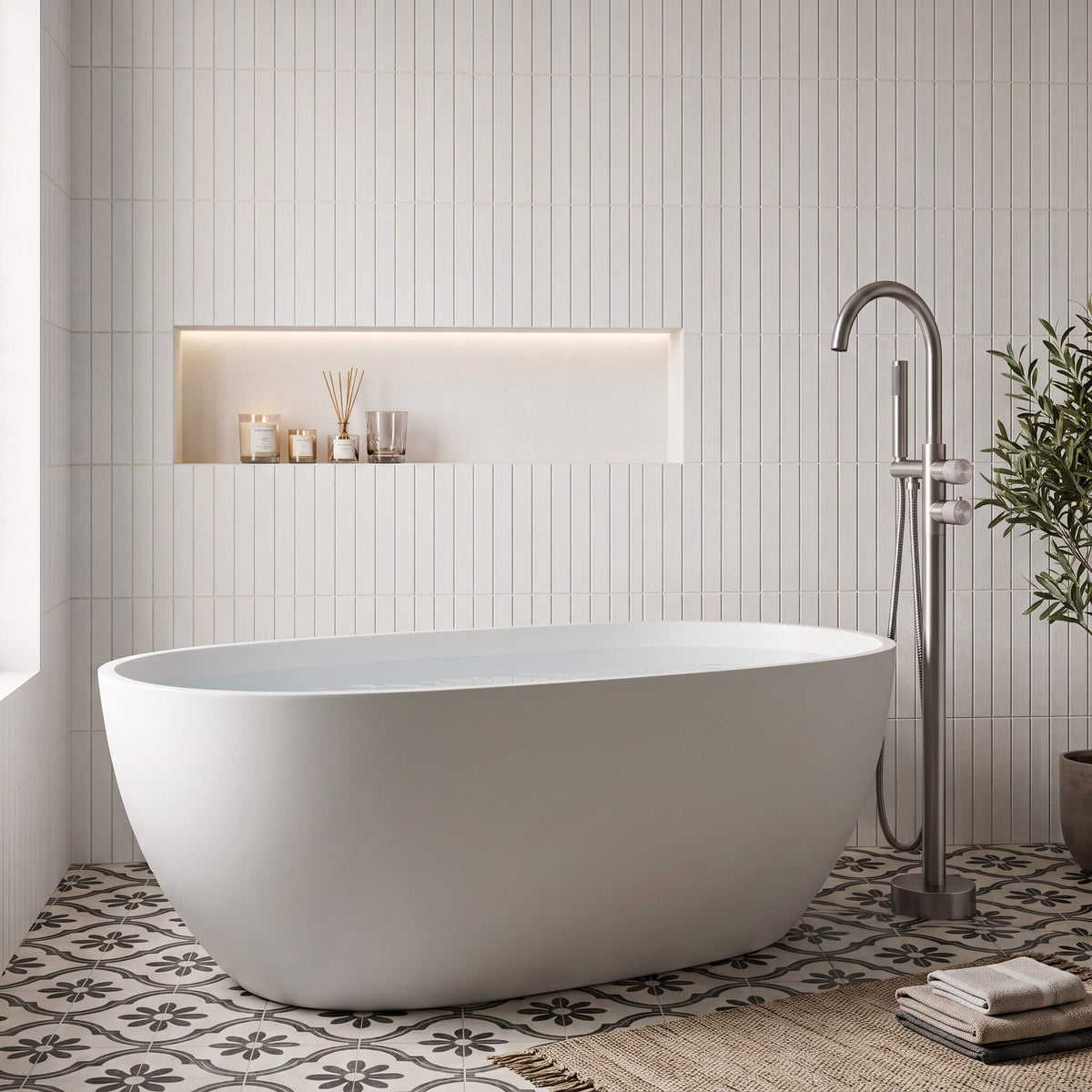 Brushed nickel floor mounted tub filler with hand shower beside a freestanding bathtub
