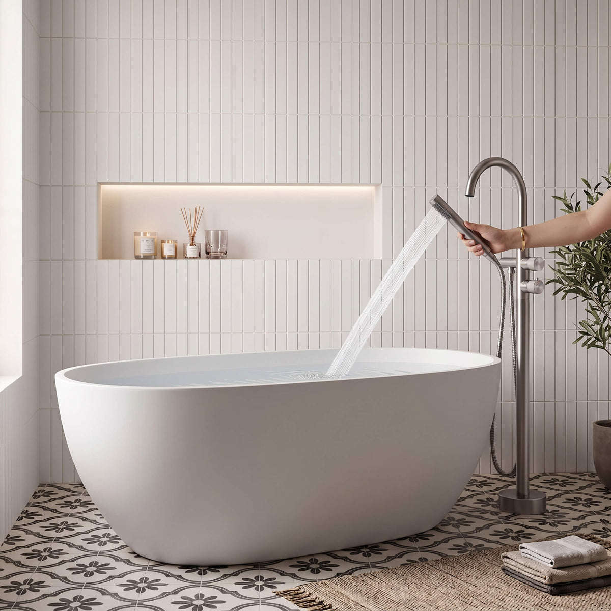 Brushed nickel freestanding tub filler with handheld shower spraying into a white bathtub