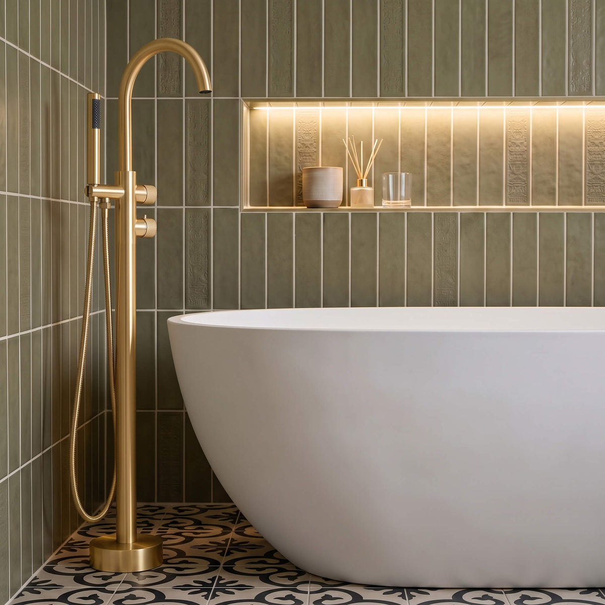 Brushed gold freestanding tub faucet with hand shower beside a white bathtub