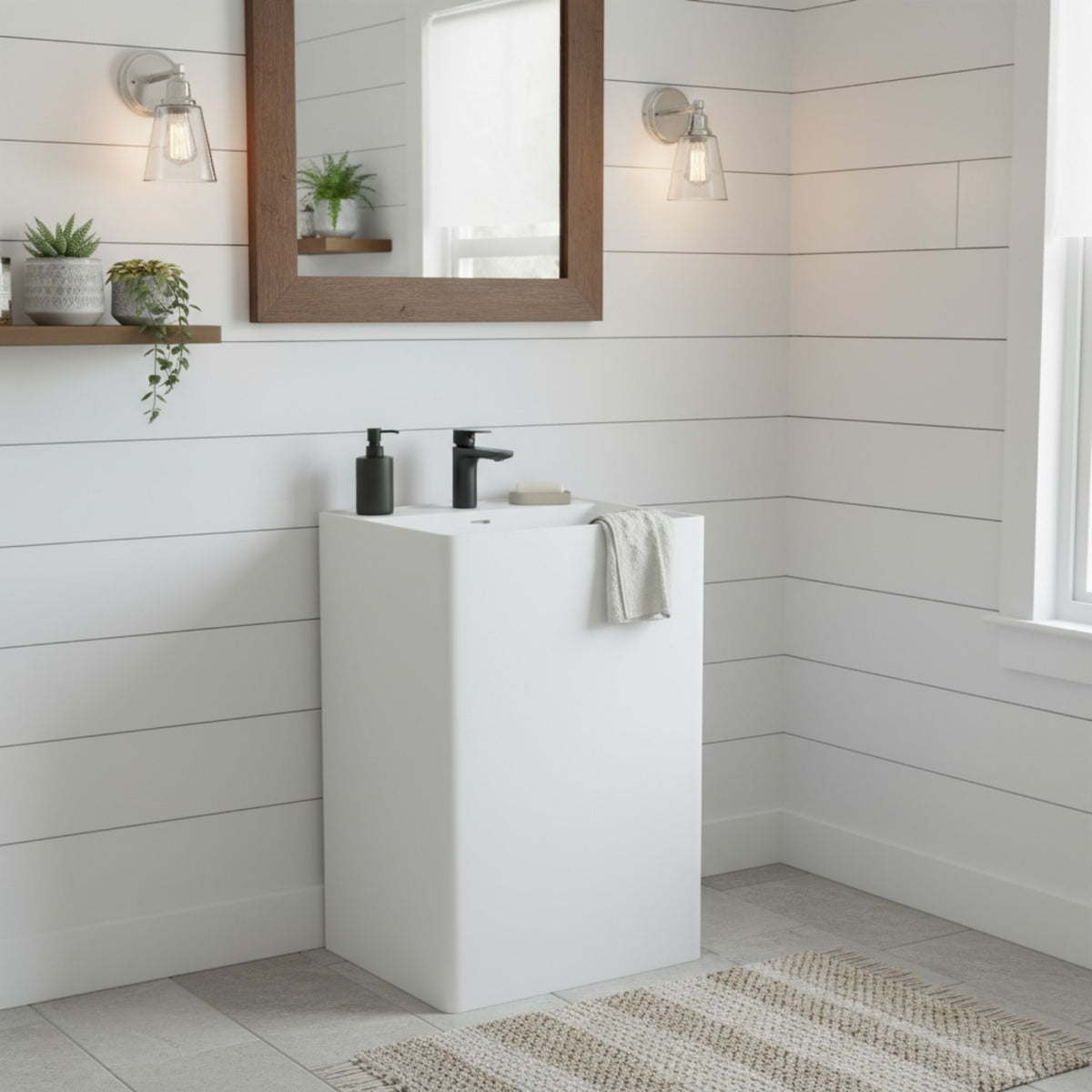 Modern bathroom interior featuring square pedestal sink in matte white resin stone with black faucet, minimalist wall lighting and wood-framed mirror.