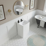 Elegant bathroom with square freestanding pedestal sink in matte white, black faucet, gold wall sconces, and clawfoot bathtub.