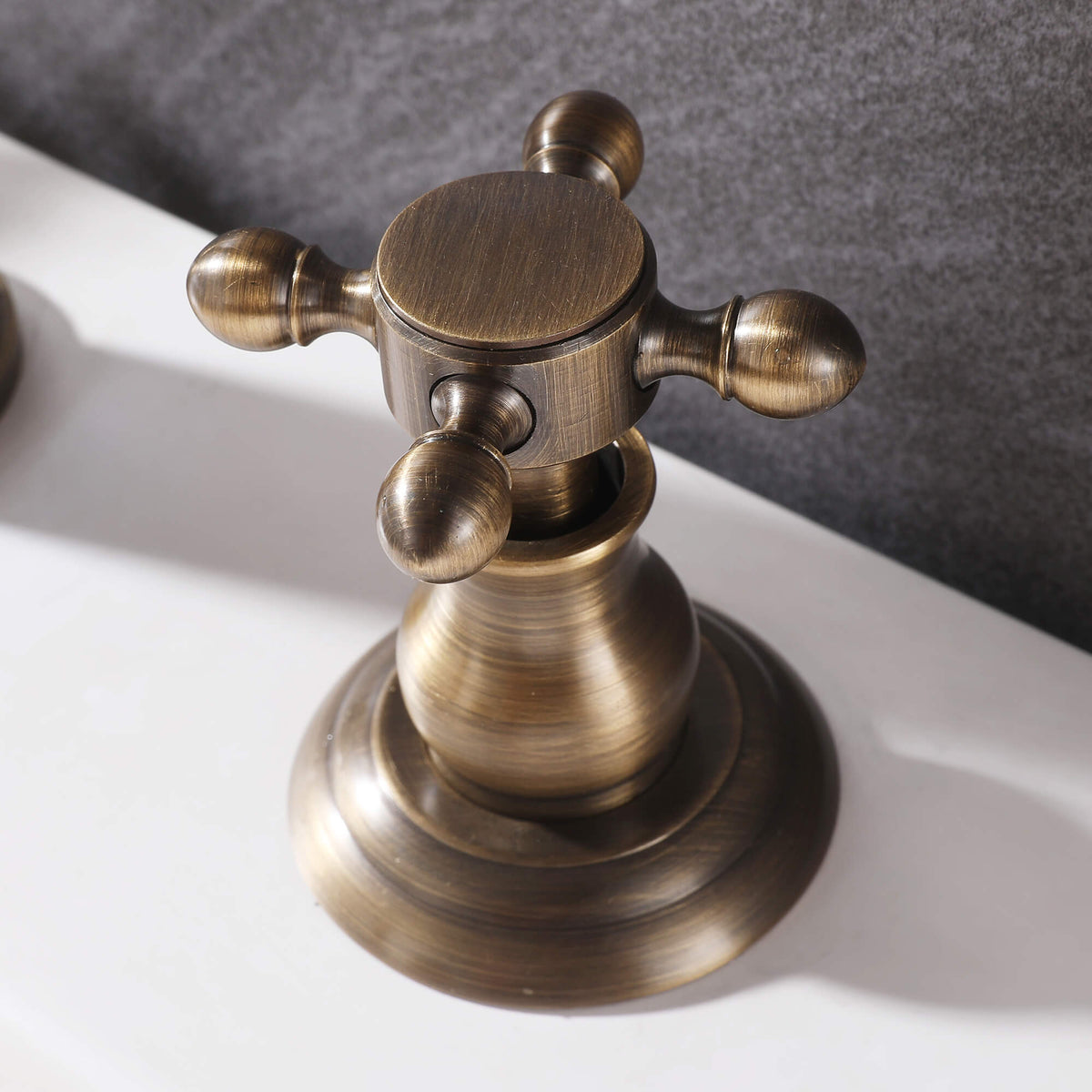 Close-up of antique brass cross handle on vintage widespread bathroom faucet