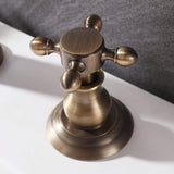 Close-up of antique brass cross handle on vintage widespread bathroom faucet