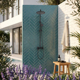 Wall-mounted outdoor shower set installed beside a pool with matte black rain shower and handheld sprayer