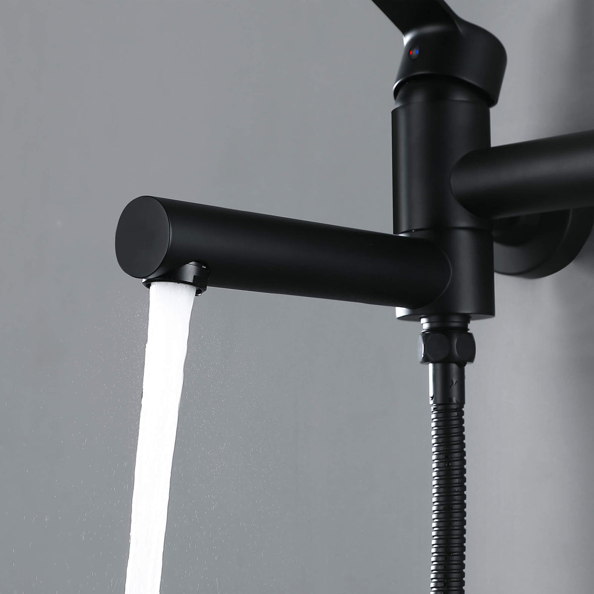 Close-up of matte black wall-mounted tub faucet spout with steady water flow